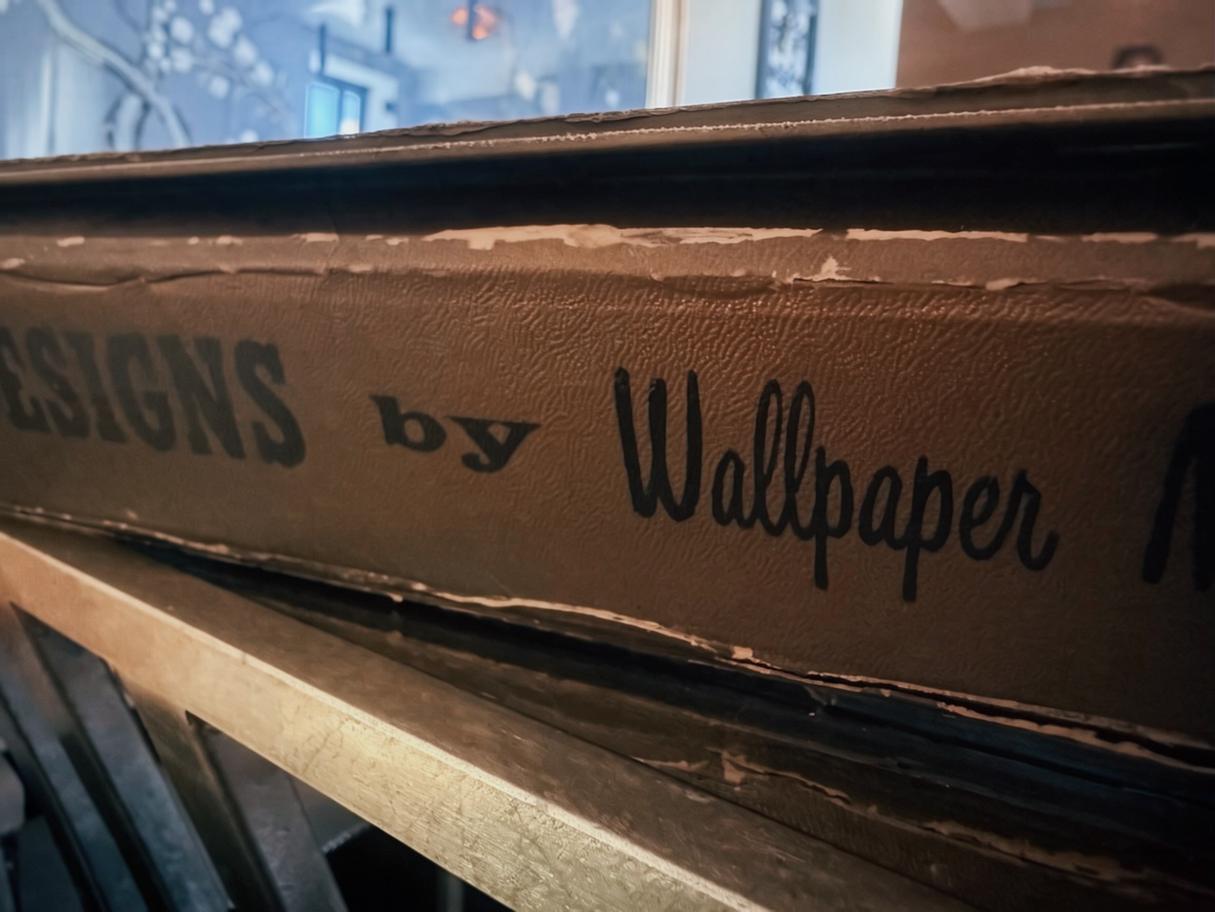 An unrolled length of antique wallpaper with an embossed botanical motif, beside its printed paper backing labeled Poetry Designs