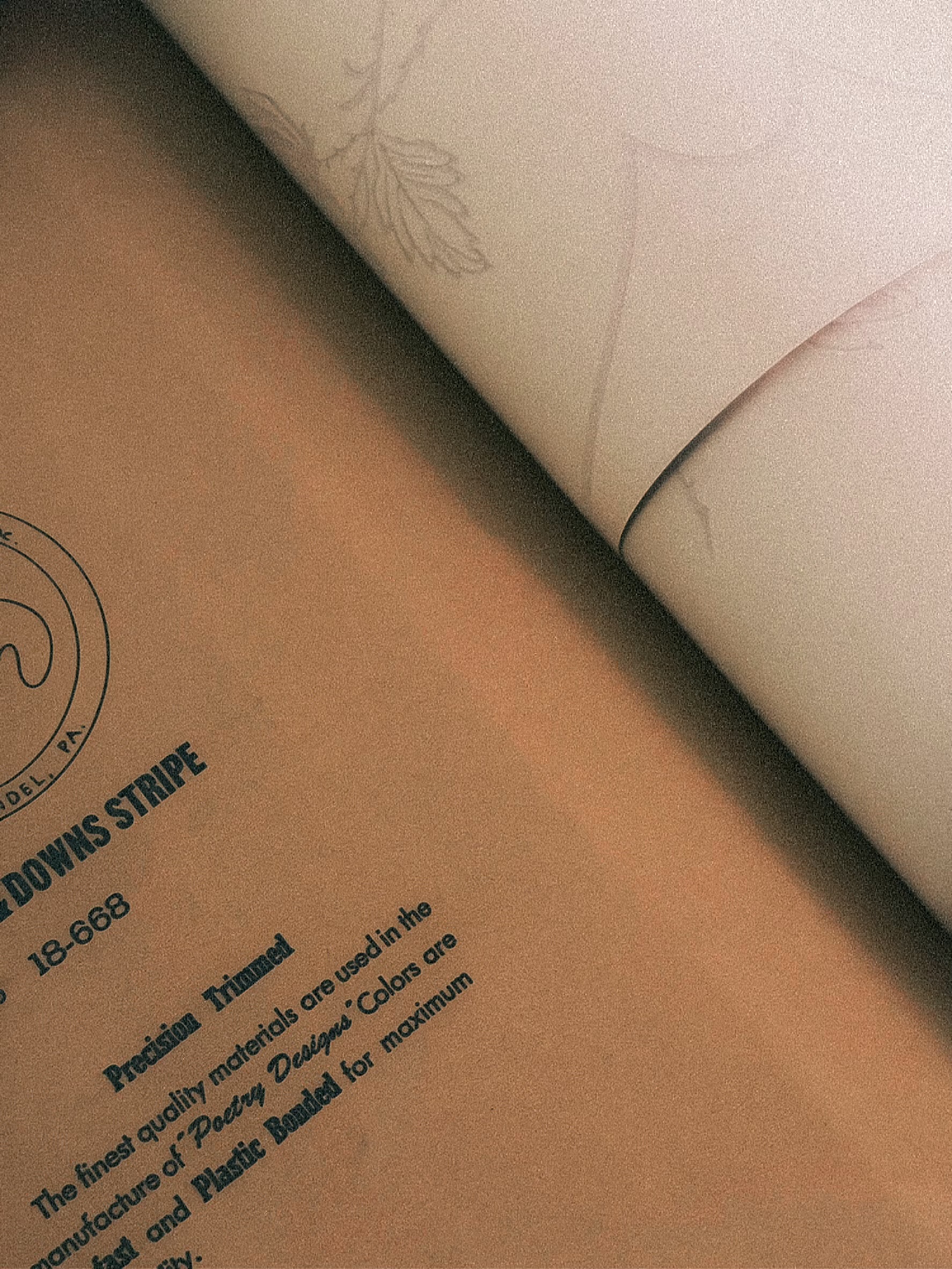 The spine of a vintage wallpaper sample book reading Designs by Wallpaper, its cloth cover worn at the edges