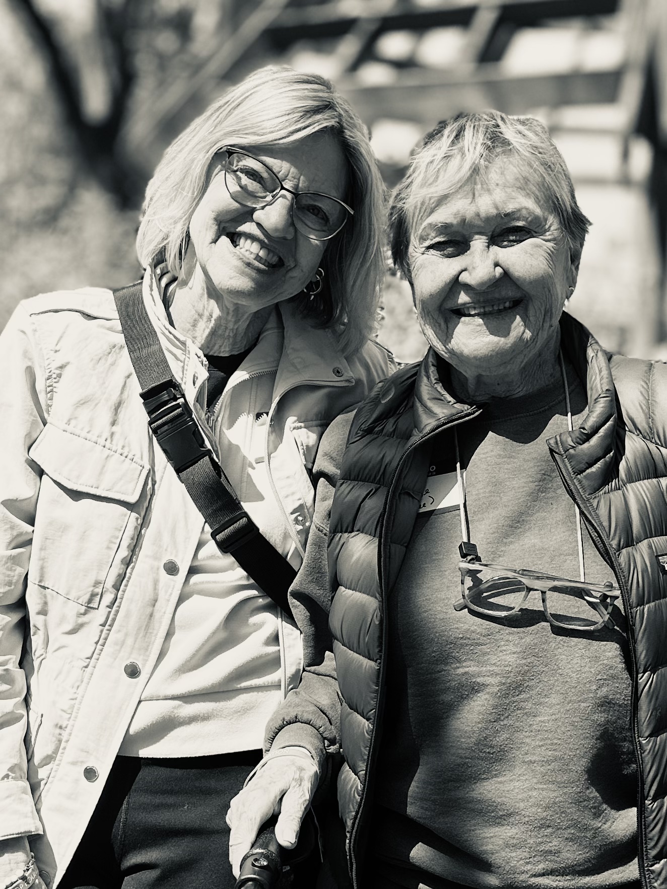 Two older women outdoors, laughing together, black and white, faces softened